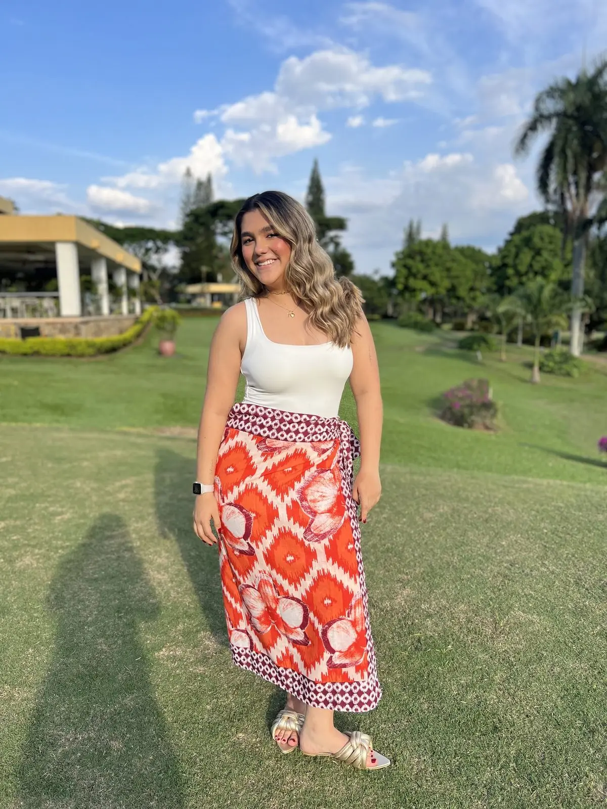 Mujer con falda pareo Orquídeas naranja y blanca en un jardín de Cali